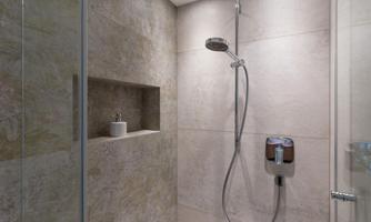 A modern shower with tile-like walls and an elegant showerhead. The space has a clean and minimalist design.