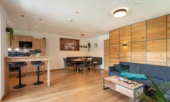 A modern apartment with an open living and dining area. The furnishings are elegant and consist of wood and cozy furniture.