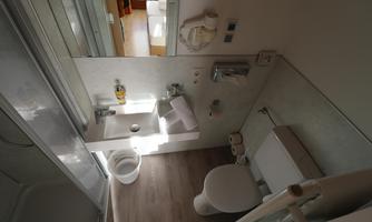 A modern bathroom with a shower, sink, and toilet. Bright colors and good lighting create an inviting atmosphere.