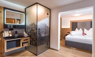 A stylish hotel room with modern design. There is a comfortable sleeping area and a separate area with a sink and mirror space.