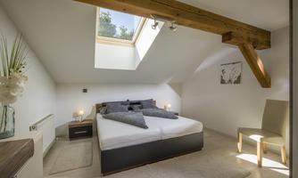 A modern bedroom with a large bed and a cozy atmosphere. The room has a window that lets in a lot of natural light.