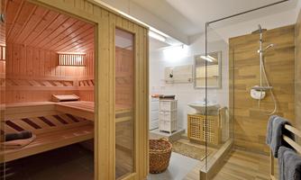 A modern bathroom with a sauna and a shower. The sauna is made of wood and the shower area is elegantly designed.