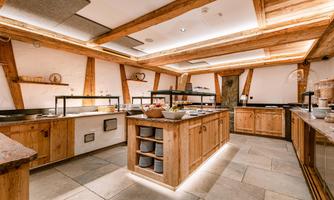 A cozy kitchen with wooden furniture and modern elements. The counter is beautifully decorated with various dishes.