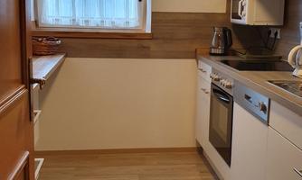 A modern kitchen with bright cabinets and wooden details. The window provides plenty of daylight.