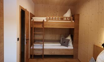 A cozy room with a wooden bunk bed. The walls are made of light wood, and there is an inviting atmosphere.