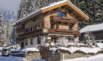 A beautiful wooden house in the snow, surrounded by tall fir trees. The snowy landscape gives the scene a picturesque atmosphere.