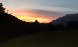 A beautiful sunset over the mountains. The colors in the sky glow in warm shades of orange and yellow.
