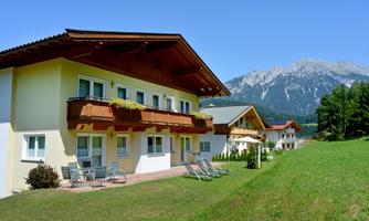 A picturesque landscape with modern houses and a mountainous backdrop. The green of the meadows and the clear air create an inviting atmosphere.
