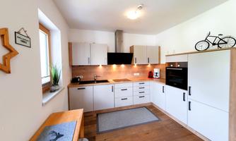 A modern kitchen with white cabinets and wood details. The room is bright and well-equipped, perfect for cooking.