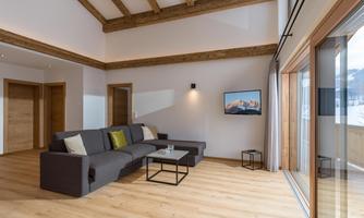 A modern living room with wooden ceilings and large windows. There is a comfortable sofa and a small table that provides relaxation.
