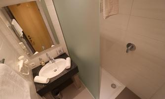 A modern bathroom with a sink and a shower. The walls are brightly tiled and there are fresh towels.