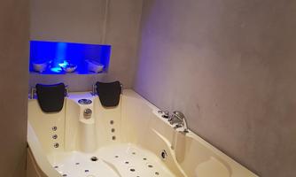 A modern bathroom with a white corner bathtub and blue LED lighting. A towel lies on the bathtub.
