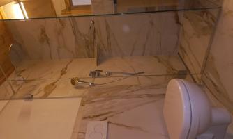 A modern bathroom with a glass shower and elegant marble. The toilet is clean and designed in a minimalist style.
