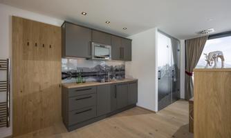 A modern kitchenette with gray cabinets and wooden details. The space is bright and friendly designed.