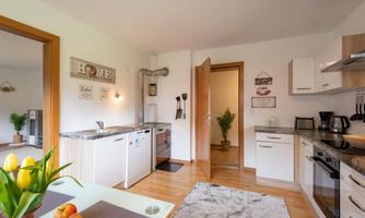 A modern kitchen with bright walls and wooden details. Fresh tulips and fruits are on the table.