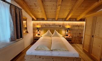 A cozy bedroom with a wooden bed and modern nightstands. The walls are made of wood, and the lighting creates a warm atmosphere.