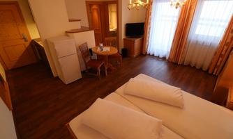 A cozy hotel room with two beds, a small table and chairs. Large windows let in plenty of light.