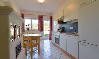 A bright kitchen with modern cabinets and appliances. A table with chairs is next to a window that lets in light.