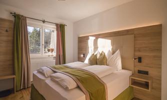 A modern bedroom with a large double bed and bright colors. Large windows provide plenty of daylight and an inviting atmosphere.