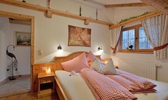 A cozy bedroom with two beds and checkered pillows. The warm wood elements and soft light create an inviting atmosphere.