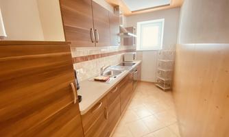 A modern kitchen with wooden furniture and bright walls. The kitchen is well-equipped and offers plenty of storage space.