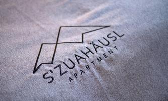 A modern logo of the apartment "S'ZUAHAEUSL". It features a minimalist design and is placed on a gray background.