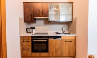 A modern kitchen with wooden cabinets and a white countertop. The equipment includes a stove, an oven, and dishes.