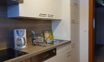 A modern kitchen with bright cabinets and a practical layout. The space includes a stove, a sink, and large electrical appliances.