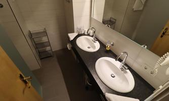 A modern bathroom with two sinks and a large mirror. The decor is simple and elegant.