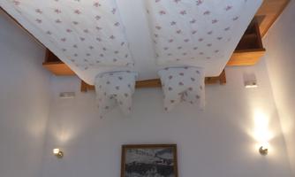 A cozy bedroom with two beds and decorative pillows. Beautiful lamps and a picture are located on the walls.