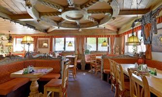 A cozy restaurant with wooden furniture and warm colors. Large windows provide plenty of light and an inviting atmosphere.