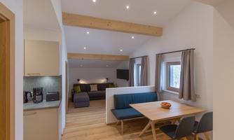 A modern apartment with an open living and dining area. Bright colors and wooden details create an inviting atmosphere.