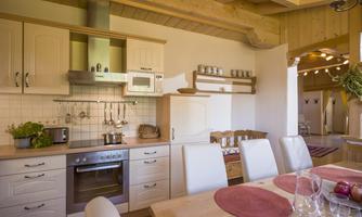 A modern kitchen with bright furniture and wooden accents. The dining area is welcoming and cozy designed.