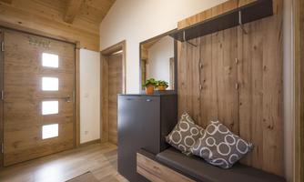 A modern entrance with wooden walls and a stylish wardrobe. A cozy seating area with decorative cushions invites you to linger.