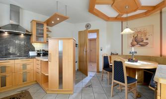 A modern kitchen with wooden furniture and a cozy dining area. The room is bright and well-structured.