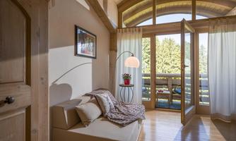 A bright living room with large windows and wood details. A cozy couch and a modern floor lamp create an inviting atmosphere.