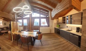A modern kitchen with wooden elements and large windows. The room is bright and inviting, ideal for sociable meals.