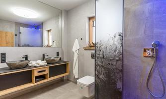 A modern bathroom with wood and stone elements. It features a shower, a chic sink, and plenty of light.