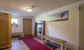 A bright entrance area with wooden flooring and rugs. A picture of hot air balloons hangs on the wall.