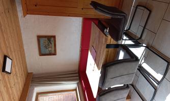 A cozy dining area with a wooden table and modern chairs. The walls are light, and there is a window with a view to the outside.