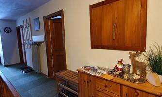 A hallway with wooden shelves and several doors. On the sideboard, there are brochures and decorative elements.