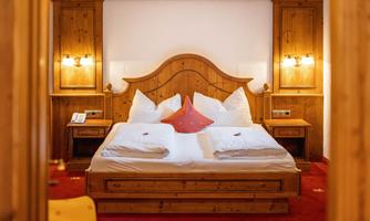 A cozy bedroom with a large wooden bed and soft pillows. The warm lighting creates an inviting atmosphere.