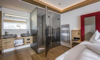 A modern hotel room with an elegant bathroom. Special features include the glass shower and the wood design.