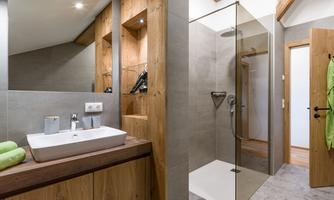 A modern bathroom with wood and stone accents. It features a spacious shower and an elegant sink.