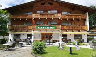 A traditional inn in alpine style with an inviting outdoor area.  
In front of the building are tables and chairs for relaxing outdoors.