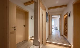 A modern hallway with wooden floors and bright walls.  
Decorative elements adorn the walls, and the area is well lit.