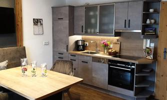 A modern kitchen with a dining table and chairs. The kitchenette is bright and well-equipped.