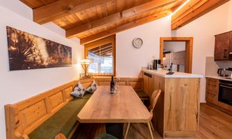 A modern kitchen with a wooden ceiling and a large dining table. The room is bright and inviting, perfect for social evenings.