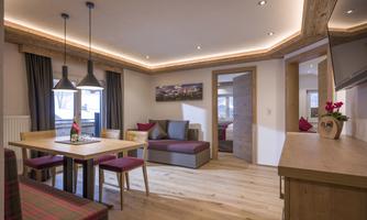 A modern apartment with a cozy dining area and stylish decor. Large windows provide plenty of light and an inviting atmosphere.