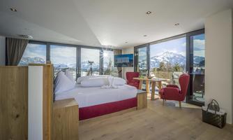 A modern room with large windows and a wonderful view of the mountains. The decor is elegant and inviting with a double bed and cozy chairs.
